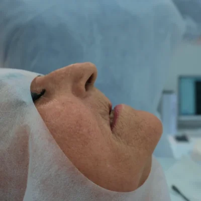 Paciente preparada para cirurgia de enxerto ósseo no centro cirúrgico do Hospital do Enxerto Ósseo, com equipe médica e monitoramento ao fundo